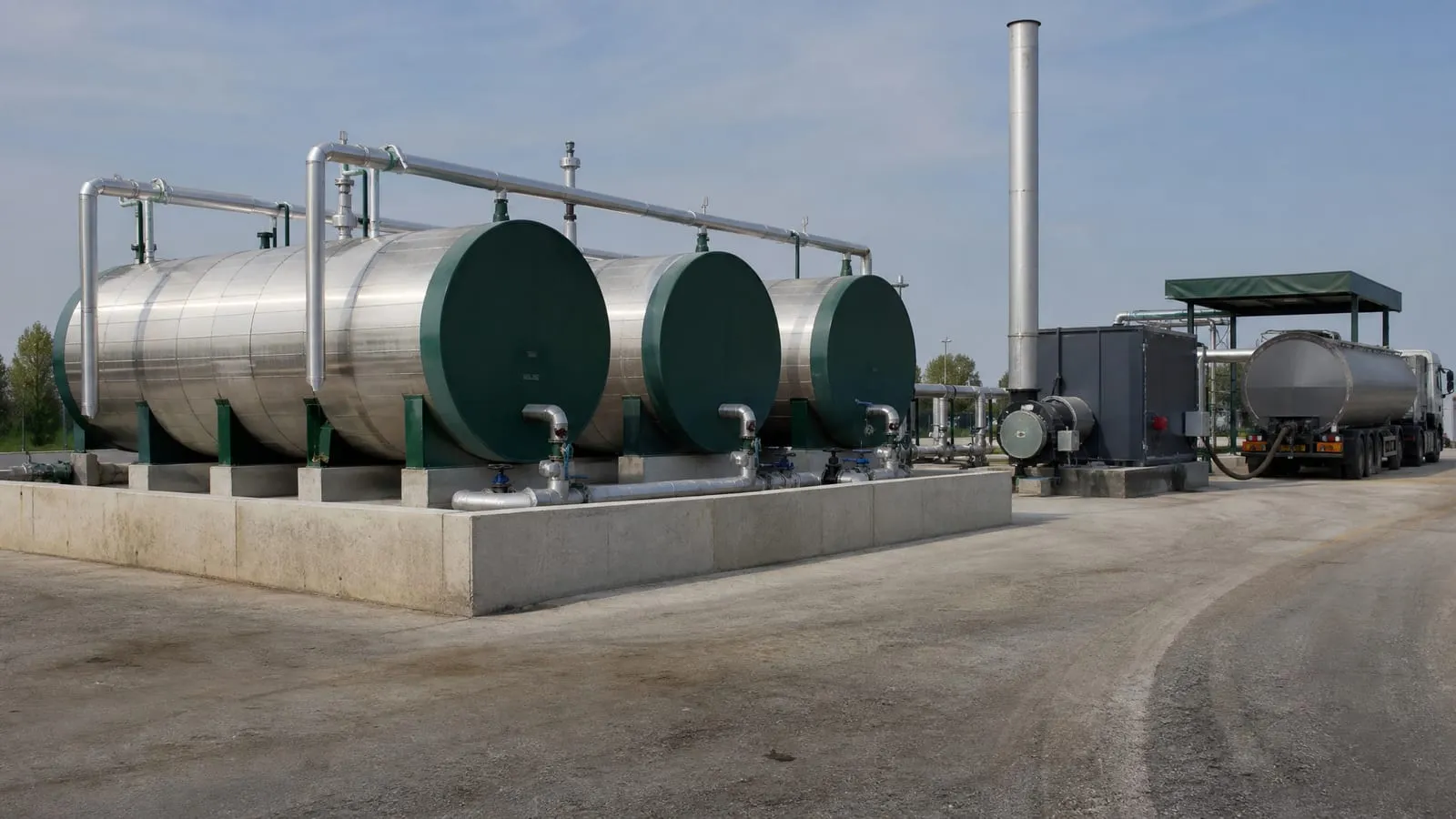 Insulated horizontal bitumen tanks in a bunded area with a thermal oil heater and a tanker at the unloading point
